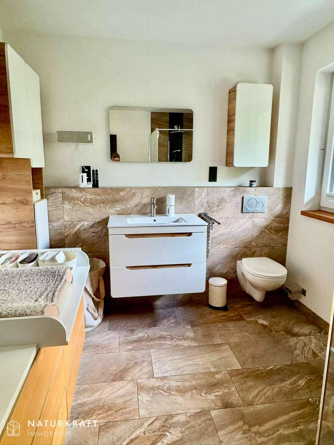 Helles Badezimmer mit modernem Waschtisch, WC und großformatigen Fliesen.