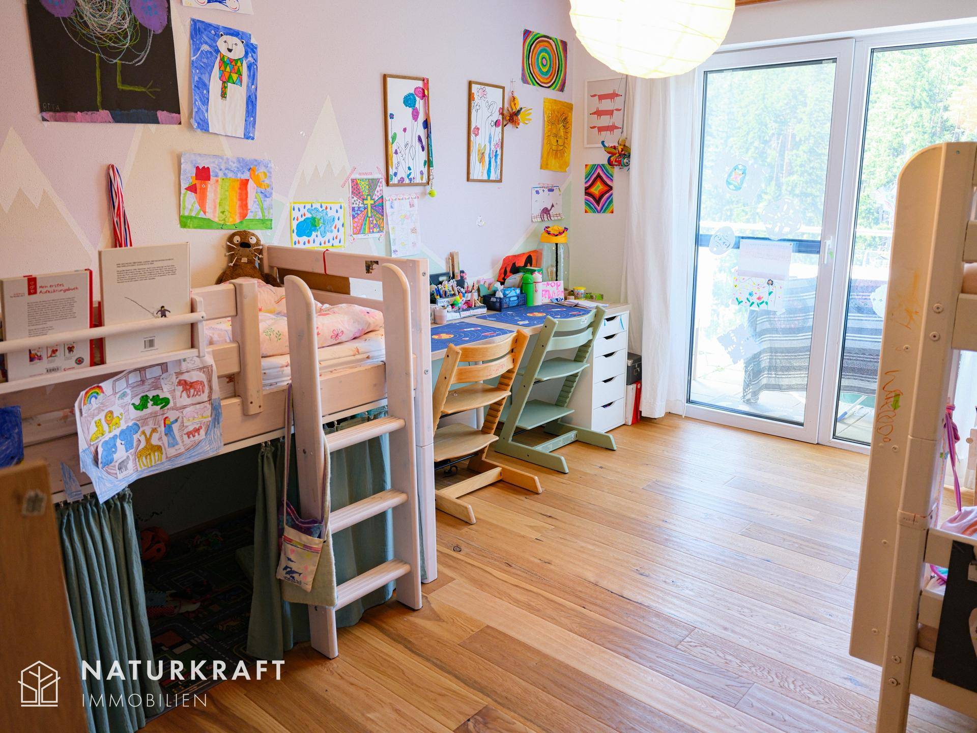 Kinderzimmer mit Hochbett, Schreibtisch und bunten Zeichnungen an der Wand, hell und freundlich.