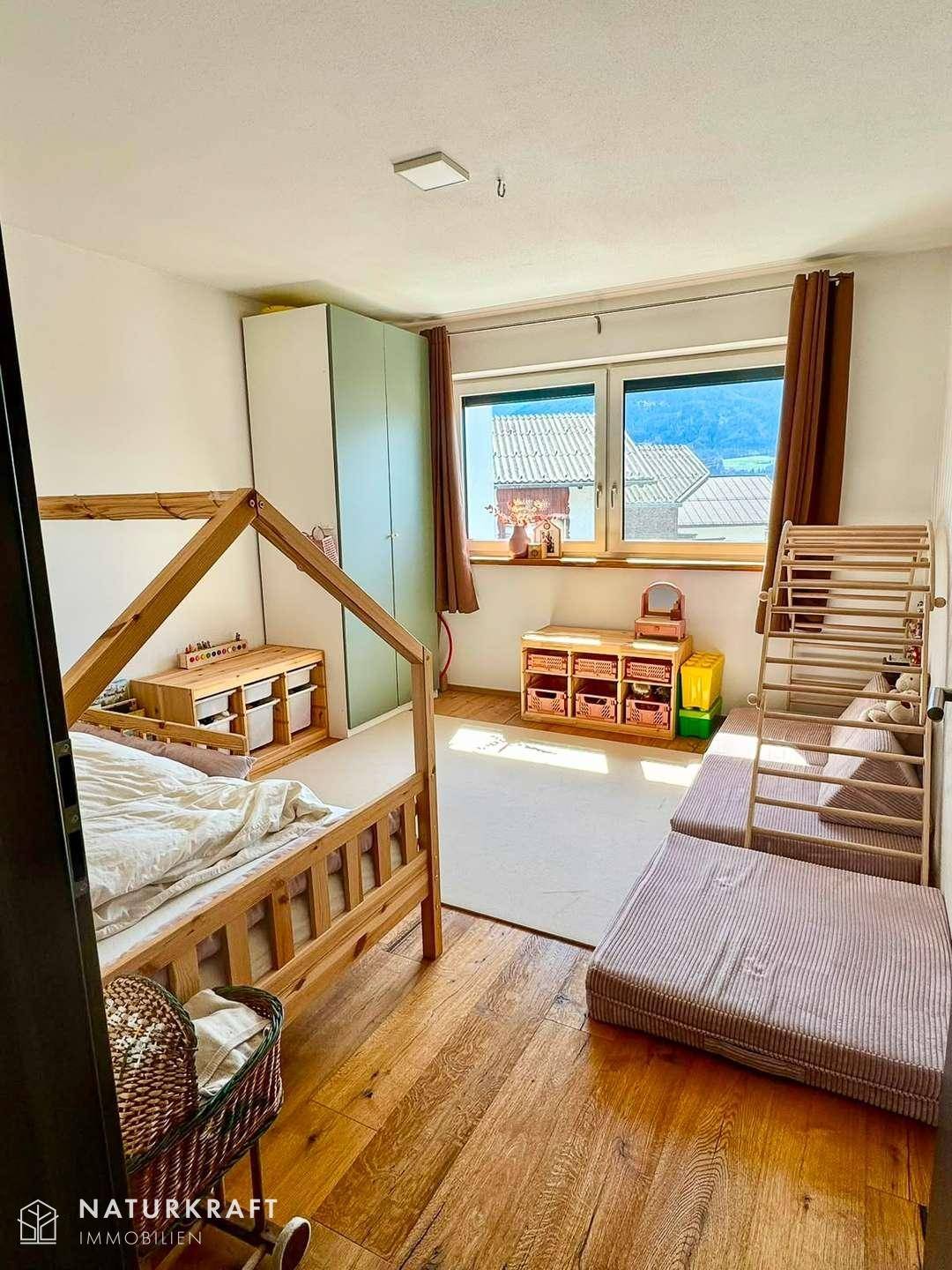 Helles Kinderzimmer mit Holzbett und Spielmatten, ideal für kleine Kinder.