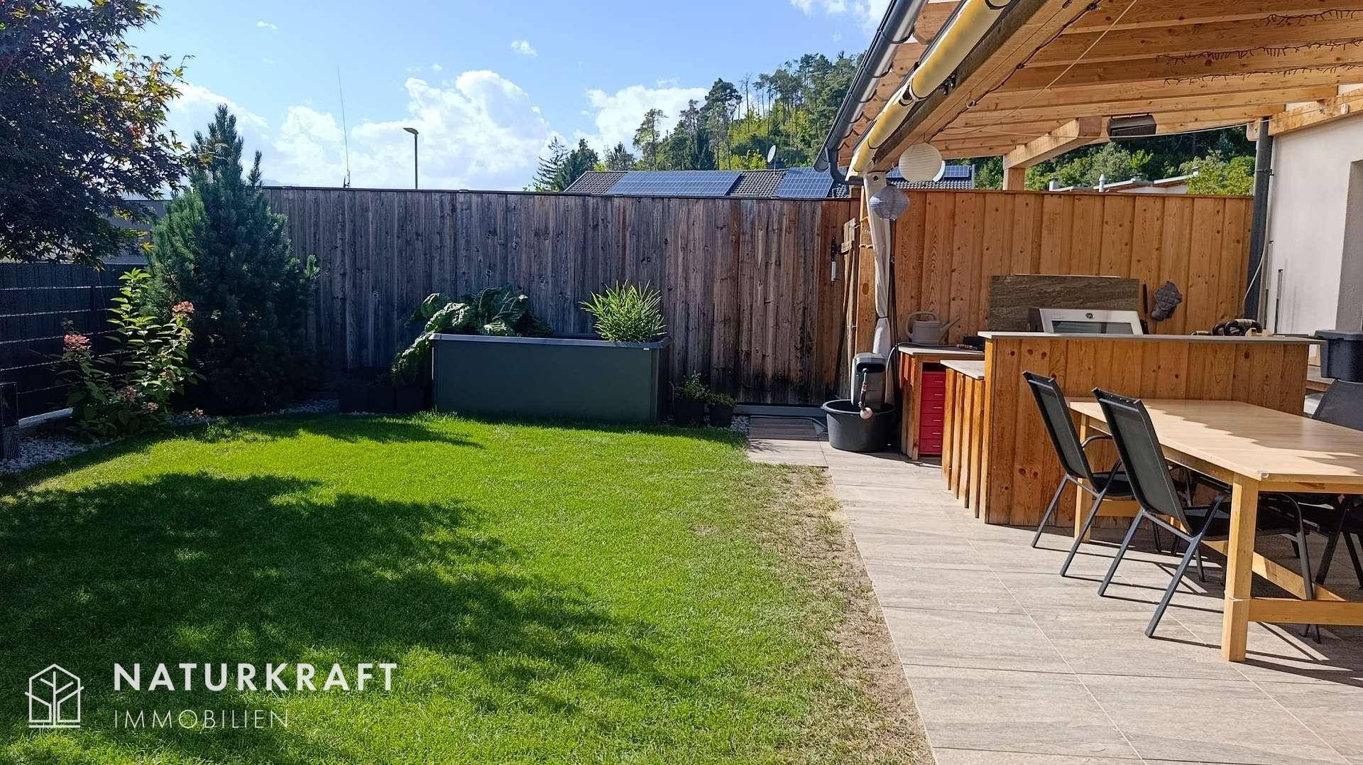 Weitläufiger Garten mit Rasenfläche und angrenzendem Essbereich im Freien.