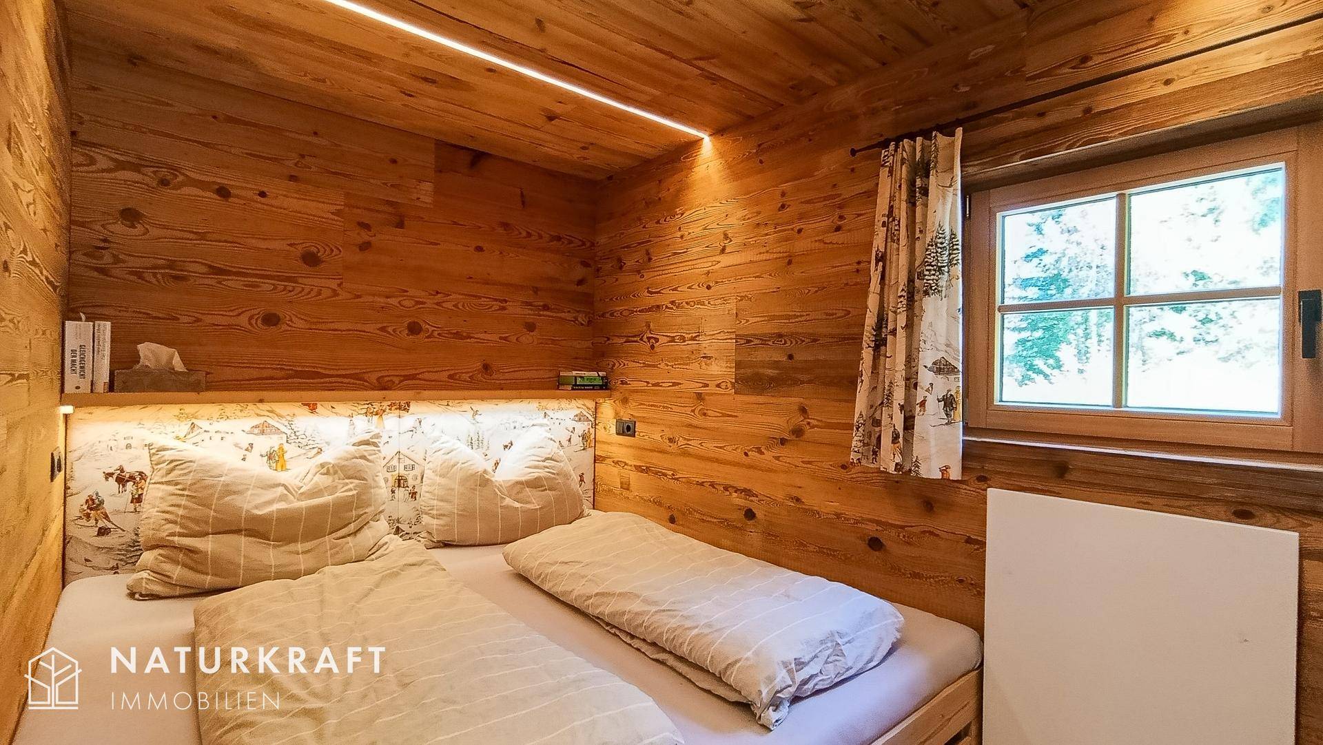 Schlafzimmer im Alpenstil mit Holzwänden, gemütlichem Bett und indirekter Beleuchtung.