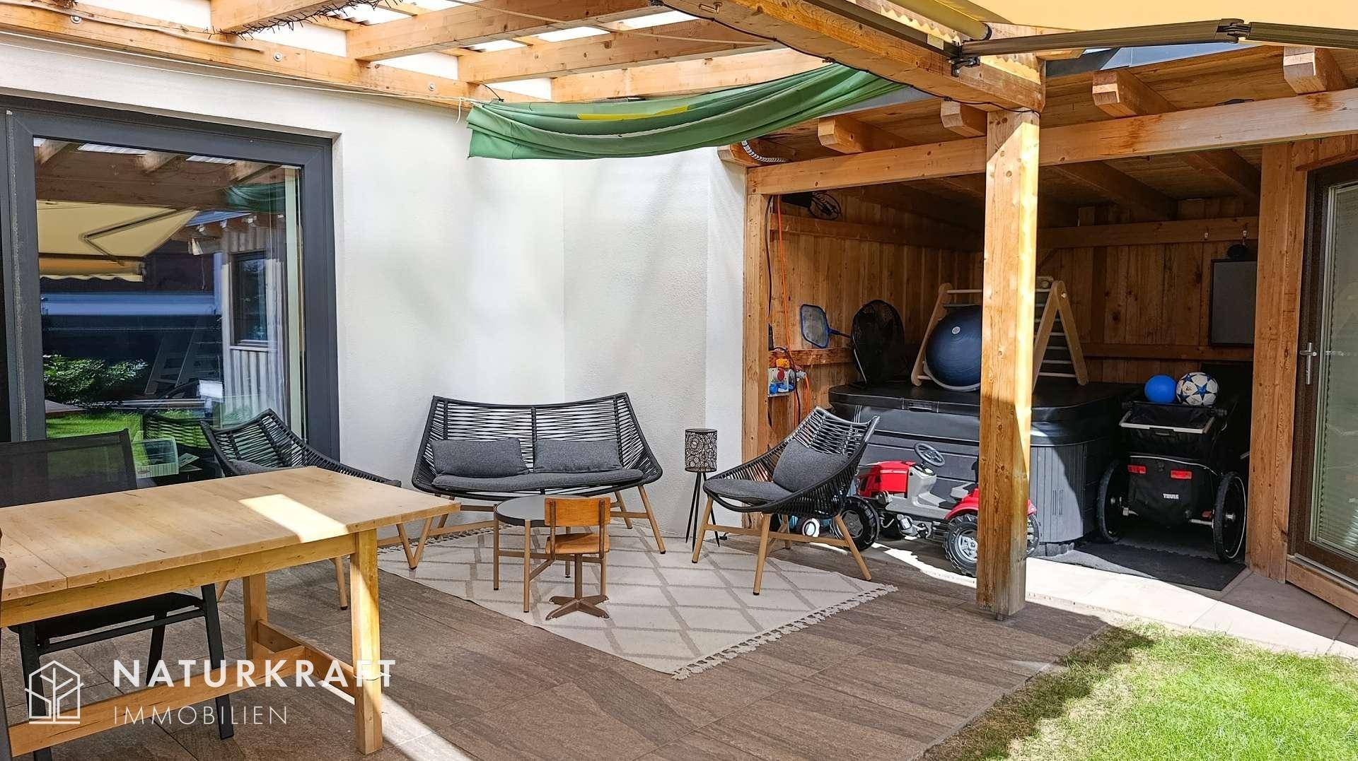 Überdachte Terrasse mit Sitzgelegenheiten und praktischem Stauraum im Freien.