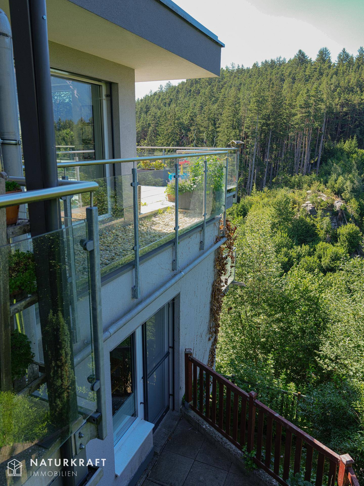 Außenansicht des Gebäudes mit mehreren Balkonen und Terrassen, umgeben von viel Grün.