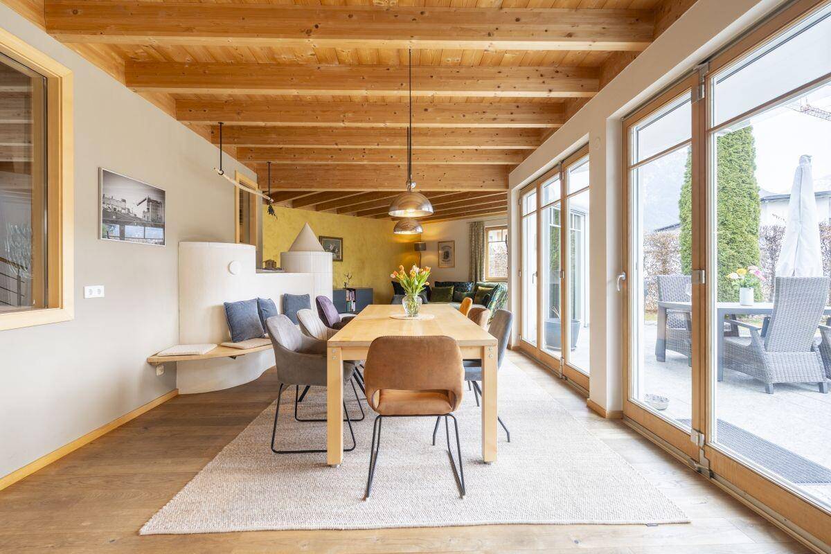 Geräumiger Essbereich mit Holzbalkendecke, großem Esstisch und Zugang zur Terrasse.