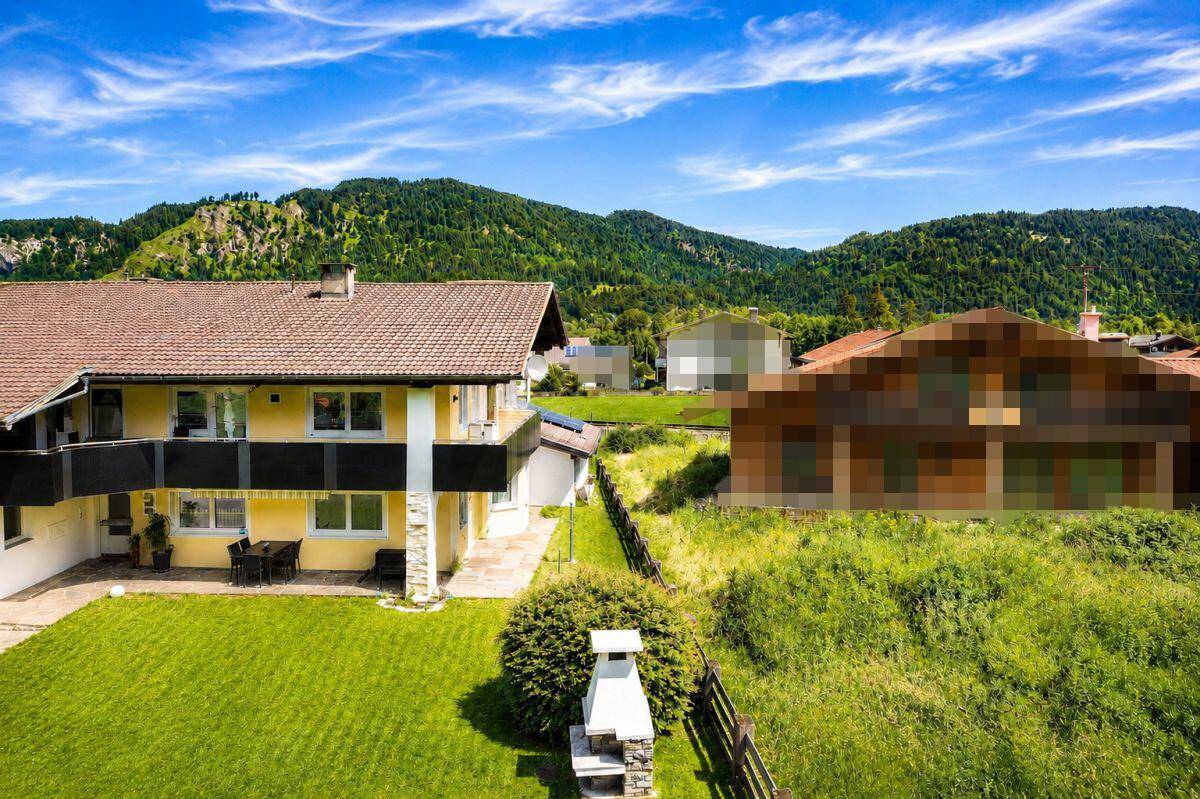 Rückansicht des Hauses mit Garten, Grillkamin und weitem Blick auf die umliegende Natur.