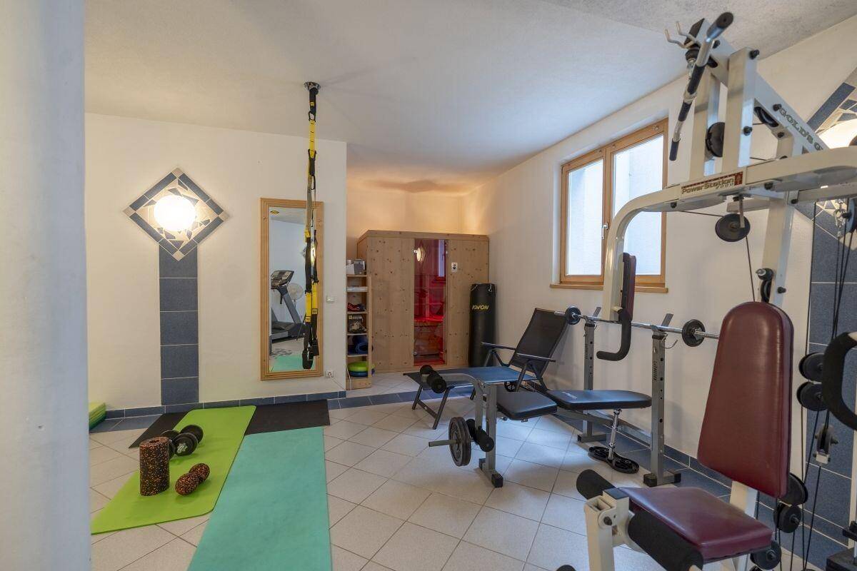 Privater Fitnessraum mit verschiedenen Geräten und einer integrierten Sauna.