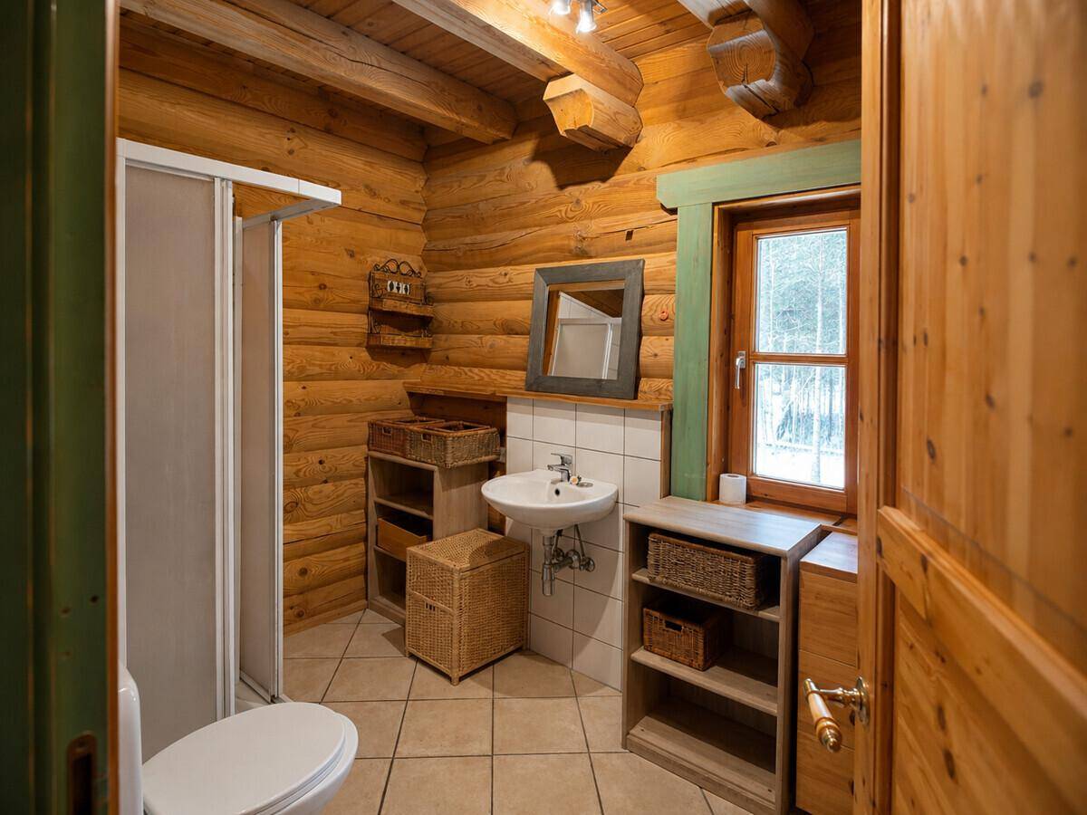 Rustikales Badezimmer mit Holzwänden, Duschkabine, Waschbecken und Fenster für Tageslicht.