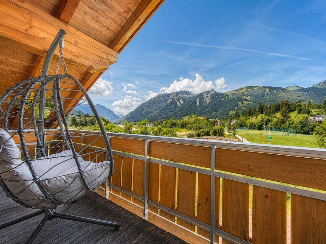 Gemütlicher Balkon mit Hängesessel und weitem Blick auf die Berge und grüne Landschaft.