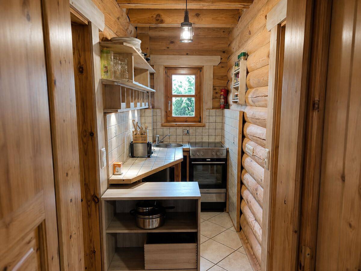 Kleine, funktionale Küchenzeile mit Holzschränken, Spüle und Kochfeld, ideal für kompakte Räume.