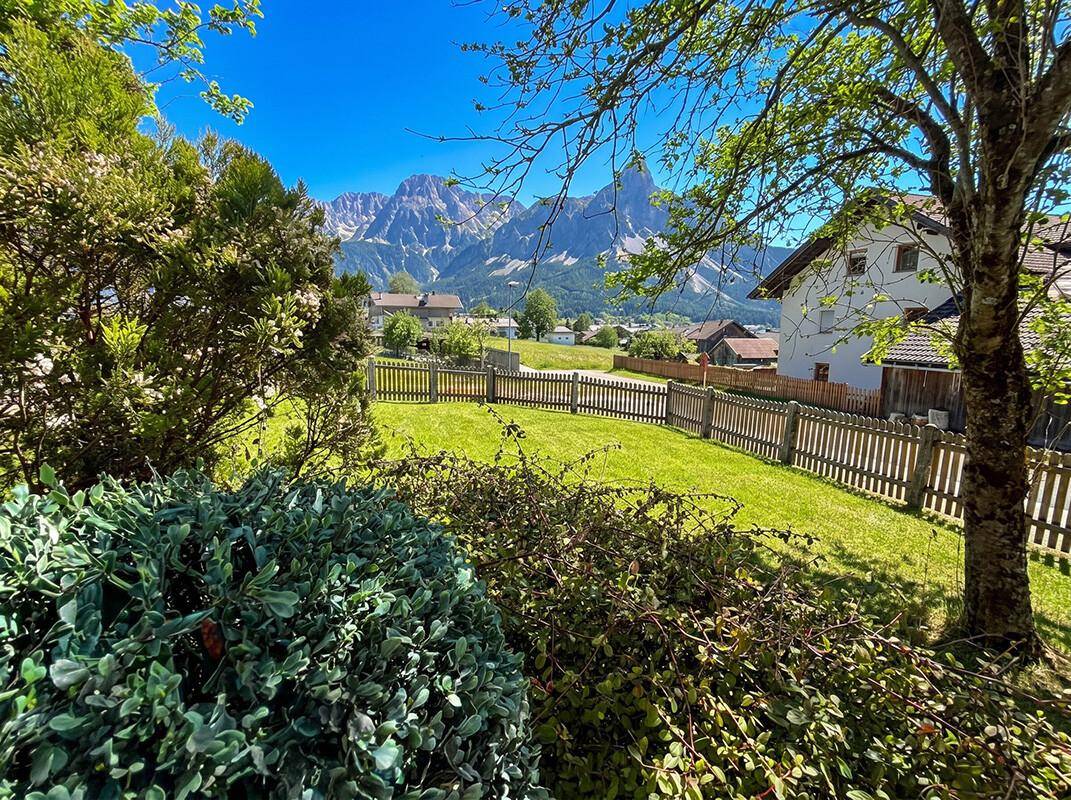 Grüner Garten mit Bäumen und Zaun, bietet einen malerischen Blick auf die Berge.