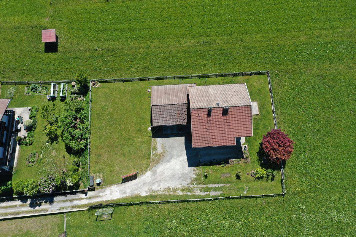 Luftaufnahme des Grundstücks mit Haus, Nebengebäude und umzäuntem Gartenbereich.