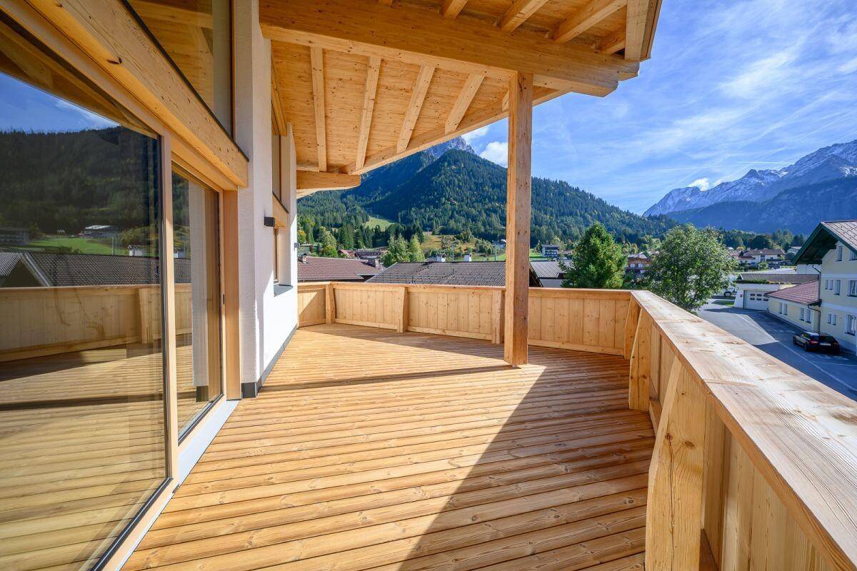 Großer Holzbalkon mit Panoramablick auf die umliegende Bergwelt und das Tal.