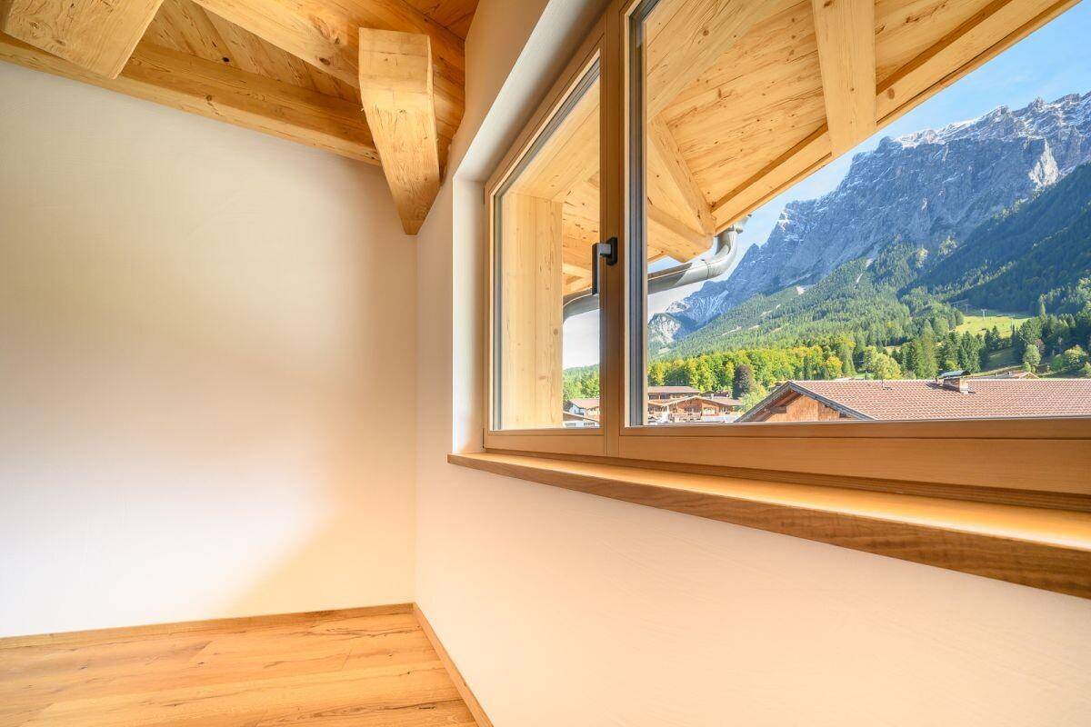 Kleiner Raum mit Holzbalkendecke und Fenster, das einen beeindruckenden Bergblick bietet.