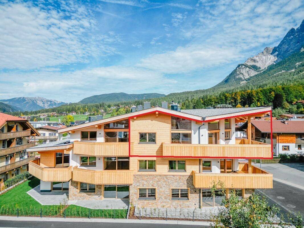 Modernes Mehrfamilienhaus in alpiner Architektur mit Balkonen und Bergblick.