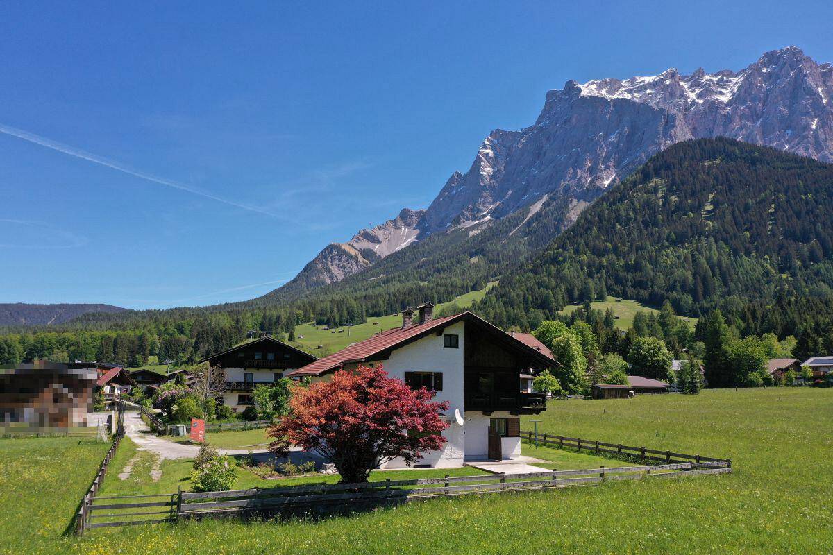 Charmantes Haus in den Alpen mit weitem Blick auf die Zugspitze und grüne Natur.