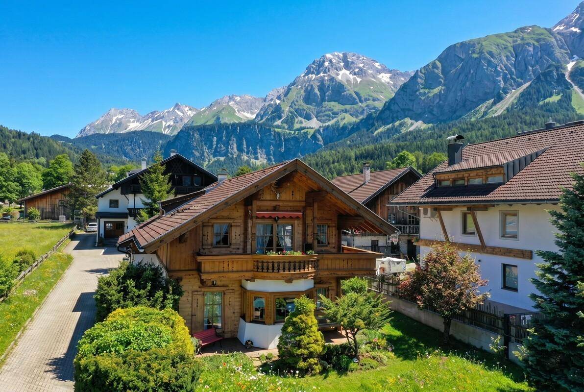 Luftaufnahme des Holzchalets in einer malerischen Berglandschaft mit umliegenden Häusern.