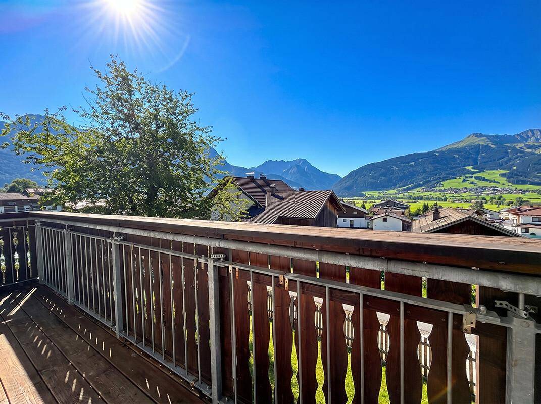 Sonniger Balkon mit Holzboden und Geländer, ideal für entspannte Stunden mit Bergblick.