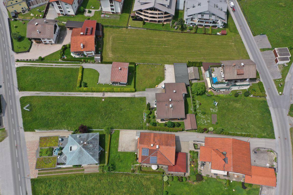 Übersicht aus der Luft auf eine Wohngegend mit verschiedenen Häusern, Gärten und einer Hauptstraße.