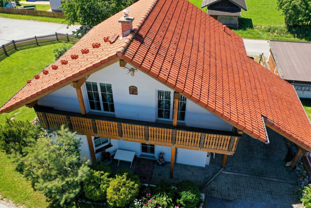 Vogelperspektive des Hauses mit rotem Ziegeldach, Balkon und gepflegtem Gartenbereich.