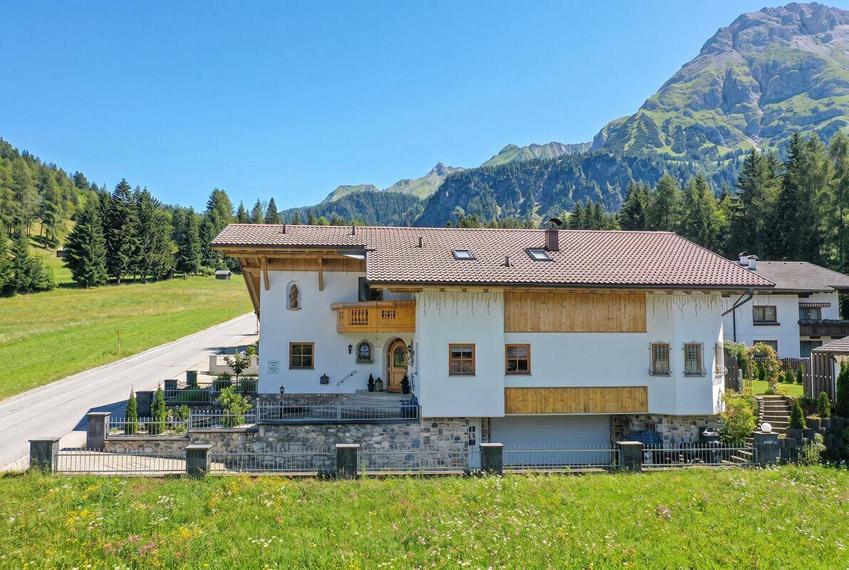 Alpines Haus mit traditionellen Elementen und weitem Blick auf die umliegende Berglandschaft.
