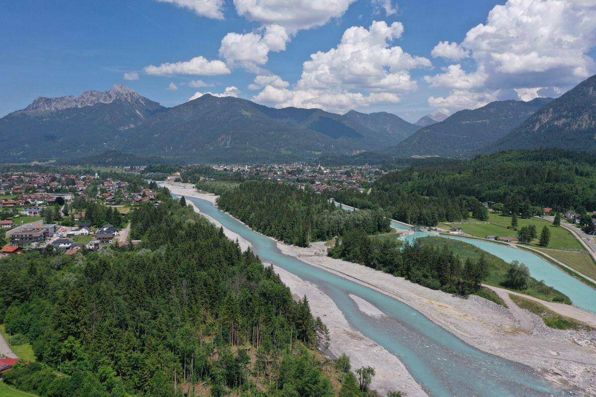 Weitläufige Flusslandschaft mit Wäldern und Bergen, umgeben von einer kleinen Stadt.