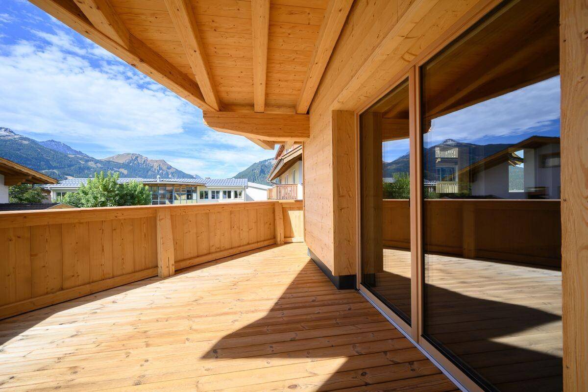 Geräumiger Holzbalkon mit Bergblick und viel Sonnenlicht, ideal für Entspannung.