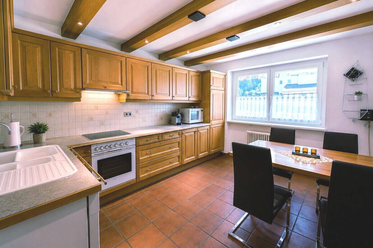 Gemütliche Wohnküche im Landhausstil mit Holzelementen, Esstisch und Terracotta-Fliesenboden.
