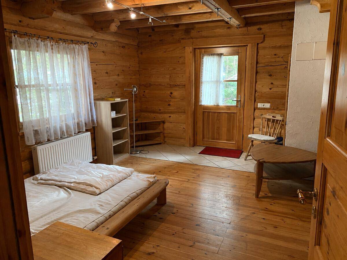 Helles Schlafzimmer mit Holzwänden, Einzelbett und Zugang zu einem Außenbereich.