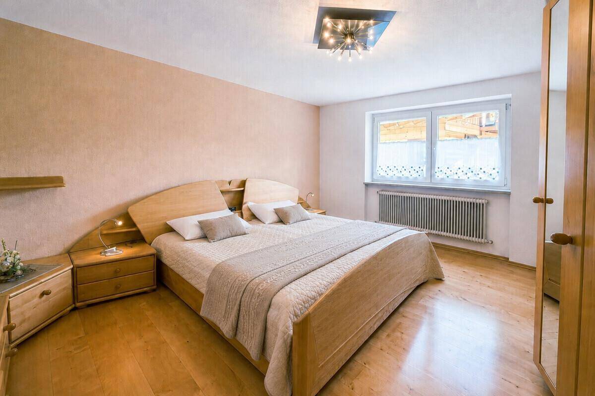 Helles Schlafzimmer mit Doppelbett, Holzmöbeln und Parkettboden.