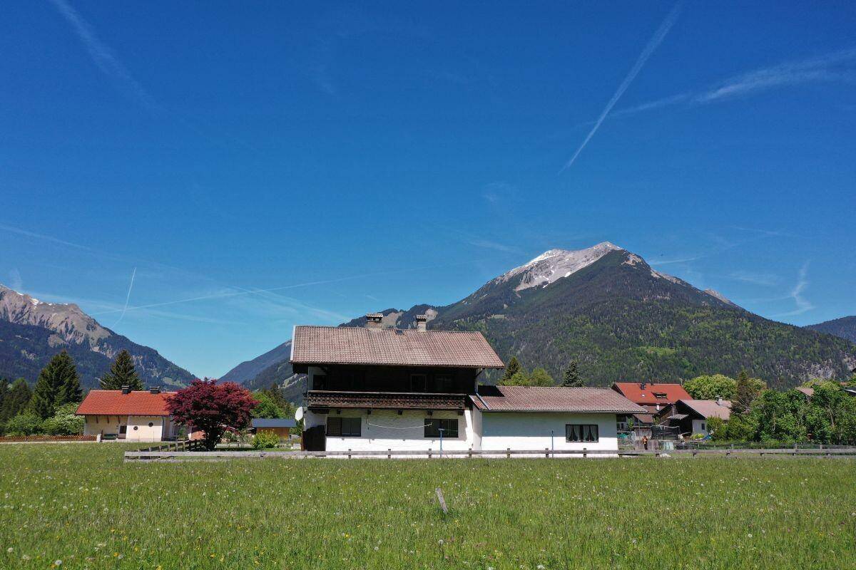 Haus in idyllischer Lage mit weitem Blick über grüne Wiesen und die umliegende Bergwelt.