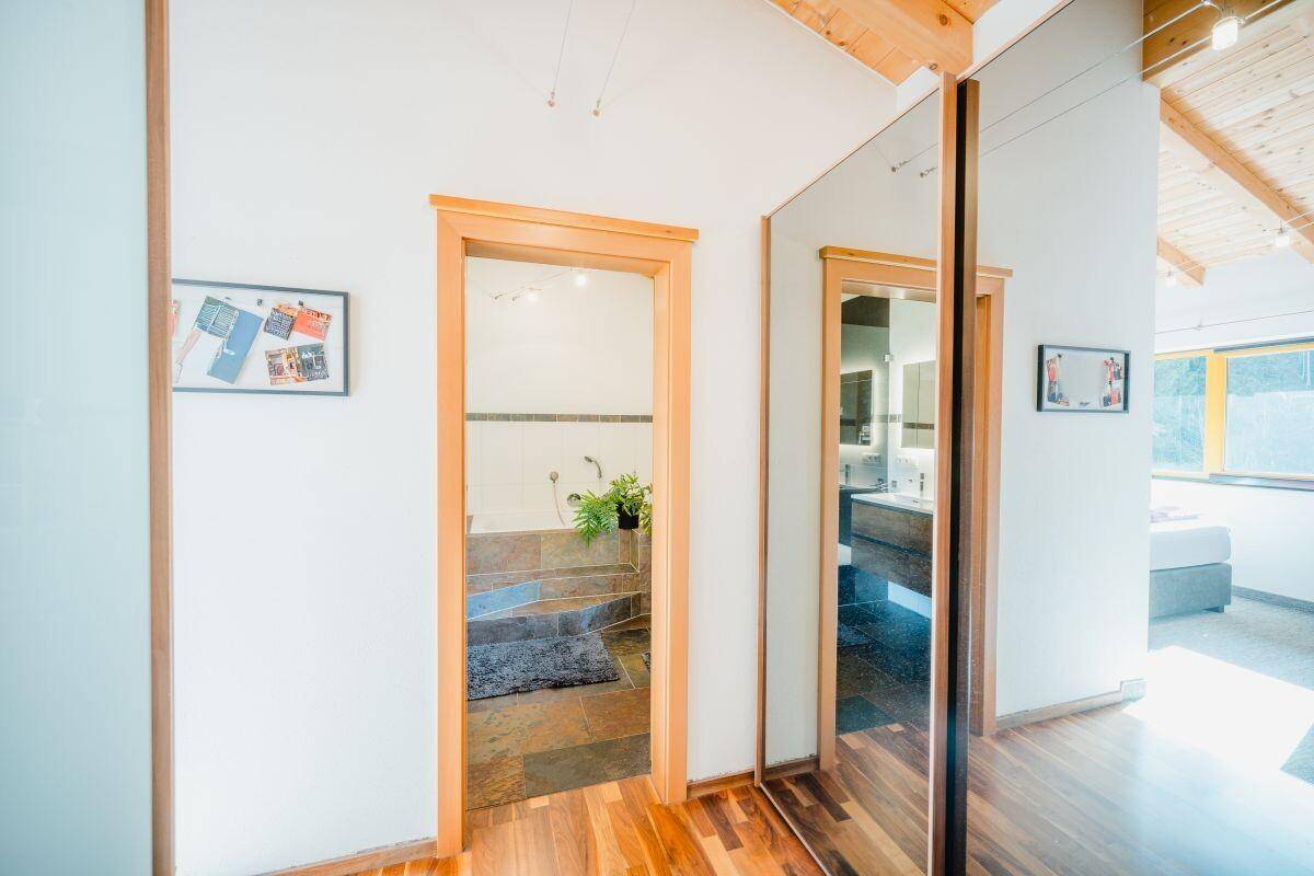 Heller Flur mit Holzfußboden und Zugang zu einem modernen Badezimmer.