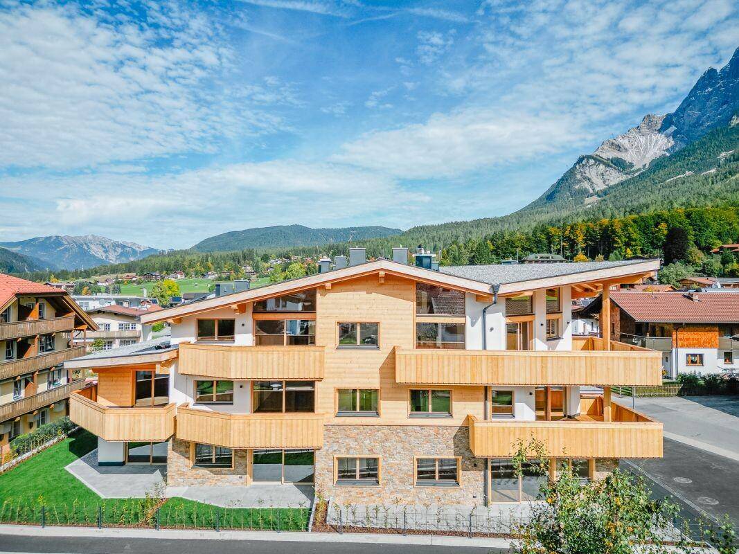 Moderne Wohnanlage mit mehreren Balkonen und atemberaubendem Bergblick, perfekt in die Natur eingebettet.
