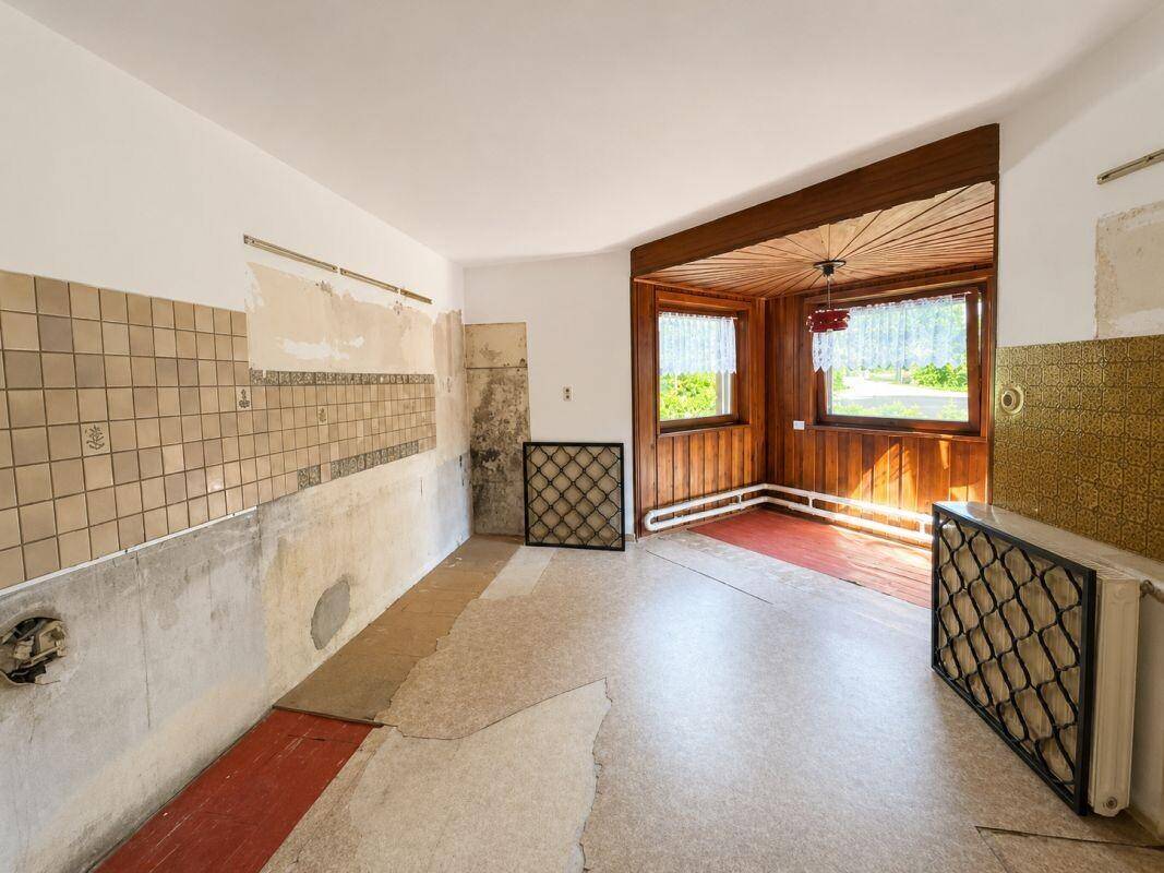 Renovierungsbedürftige Küche mit alten Fliesen und Holztäfelung, bietet Potenzial zur Modernisierung.