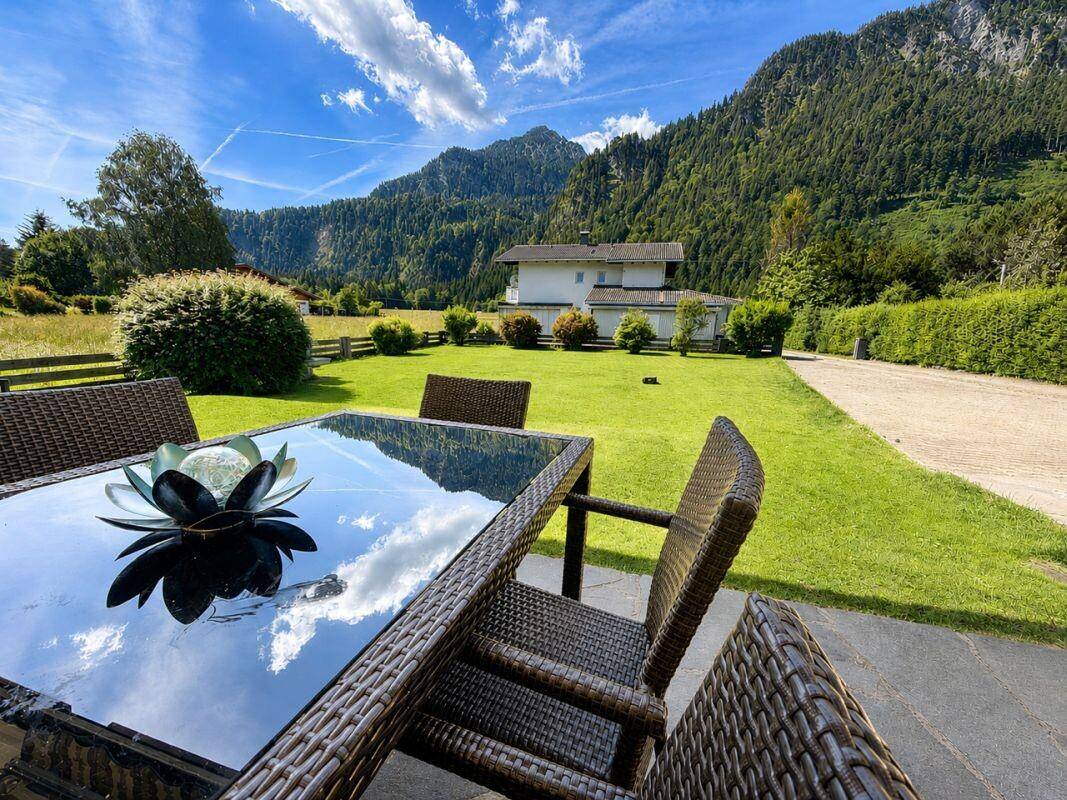 Sonniger Außenbereich mit Rattanmöbeln und weitem Blick auf die grüne Landschaft.