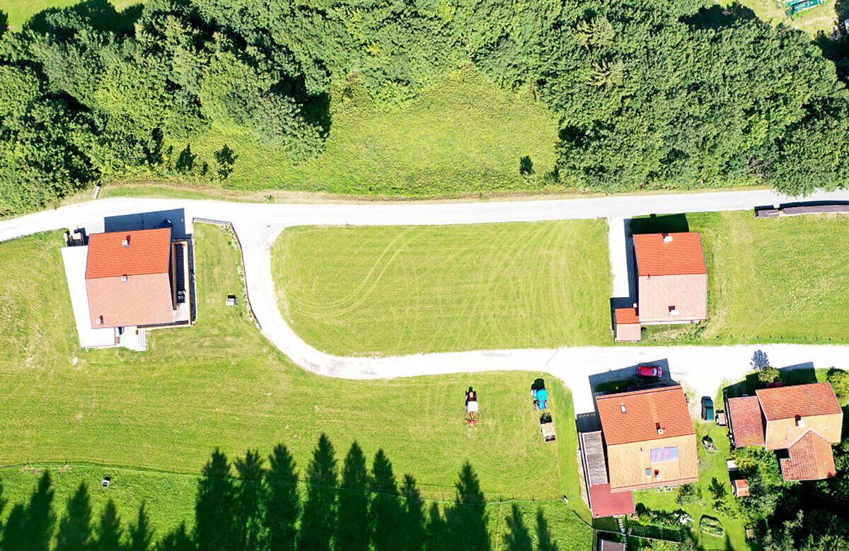 Luftaufnahme einer ländlichen Siedlung mit mehreren Häusern, Straßen und grünen Grundstücken.