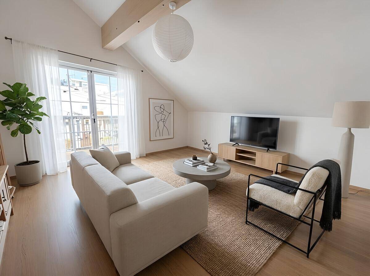 Modern eingerichtetes Wohnzimmer mit Holzbalken, Parkettboden und Balkonzugang.