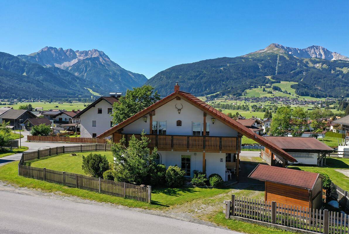 Alpines Wohnhaus mit Holzbalkon und weitem Blick auf die umliegende Bergwelt.