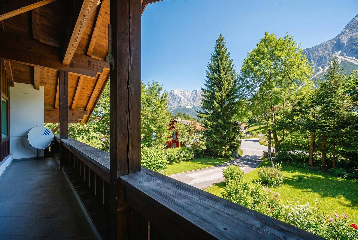 Geräumiger Holzbalkon mit Panoramablick auf die umliegende Berglandschaft und grüne Umgebung.
