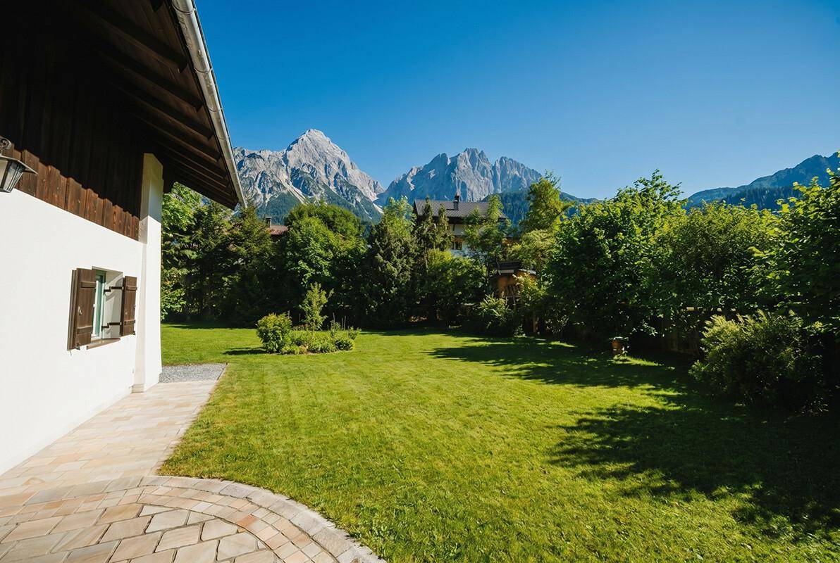 Weitläufiger Rasenbereich mit Blick auf die majestätische Berglandschaft unter blauem Himmel.