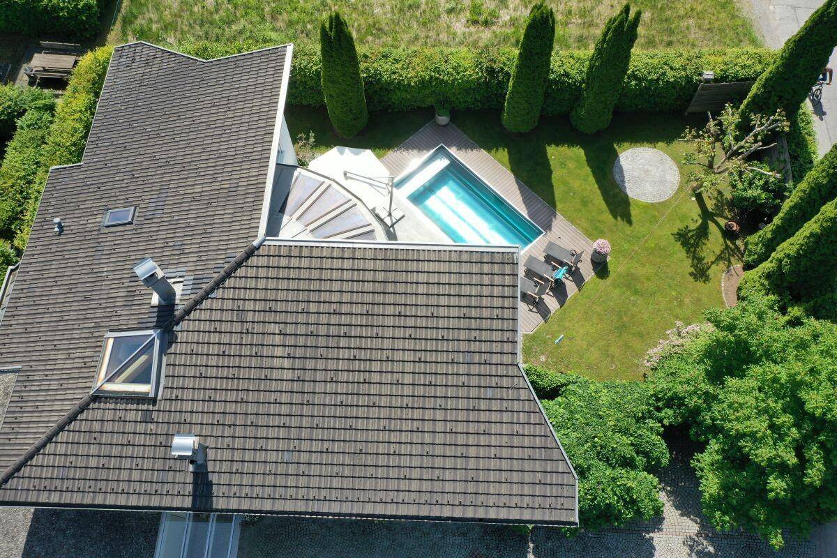 Luftaufnahme des Hauses mit Satteldach, Garten, Pool und umliegender grüner Landschaft.