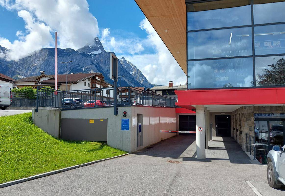 Eingangsbereich einer Tiefgarage mit moderner Architektur und Bergblick.