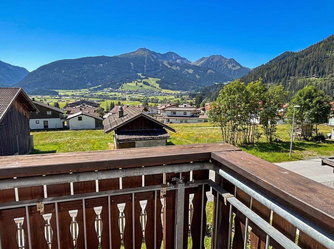 Balkon mit Holzboden und Geländer, bietet einen weiten Blick auf die grüne Landschaft.