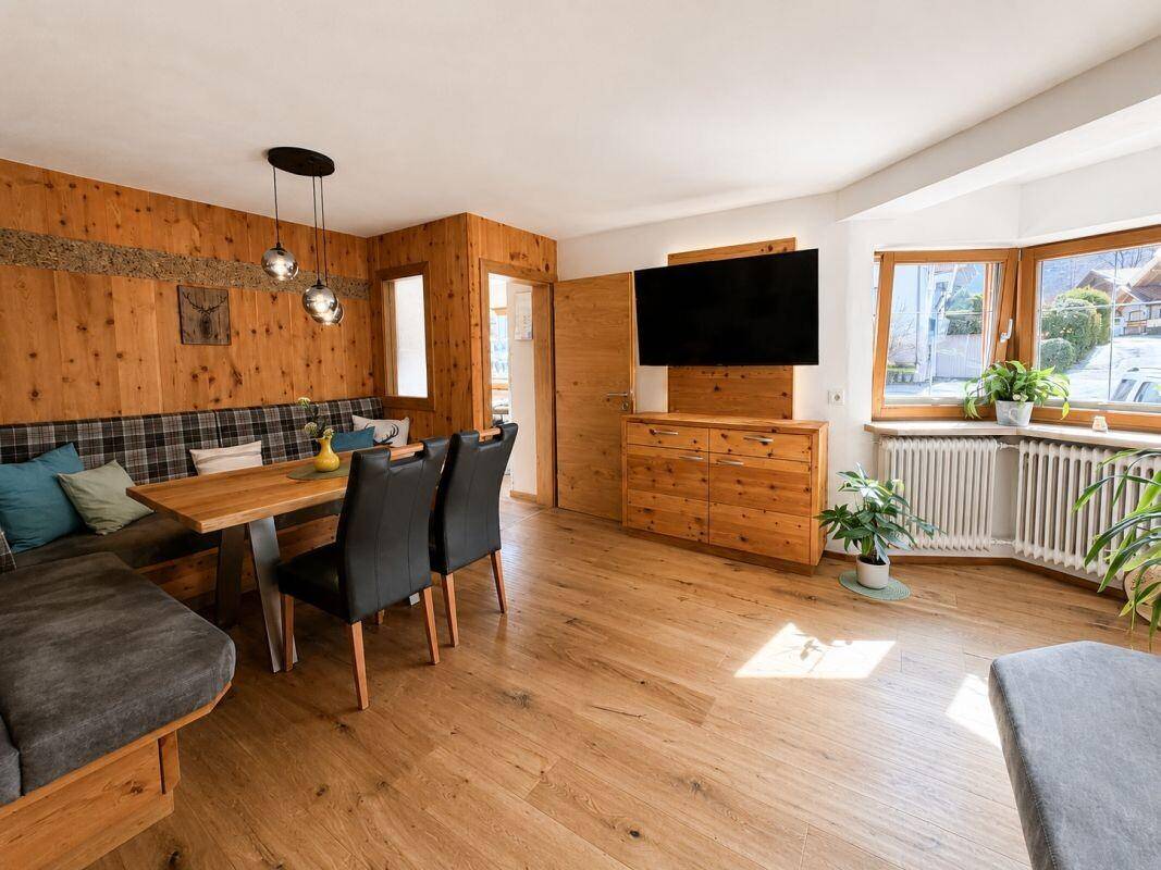 Gemütlicher Wohn-Essbereich mit Holztäfelung, Eckbank und Esstisch, hell durch Erkerfenster.