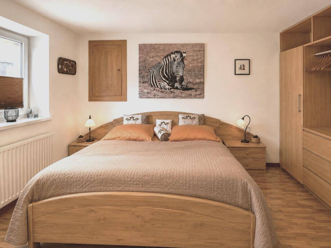 Komfortables Schlafzimmer mit Holzbett, Kleiderschrank und Blick ins Grüne.