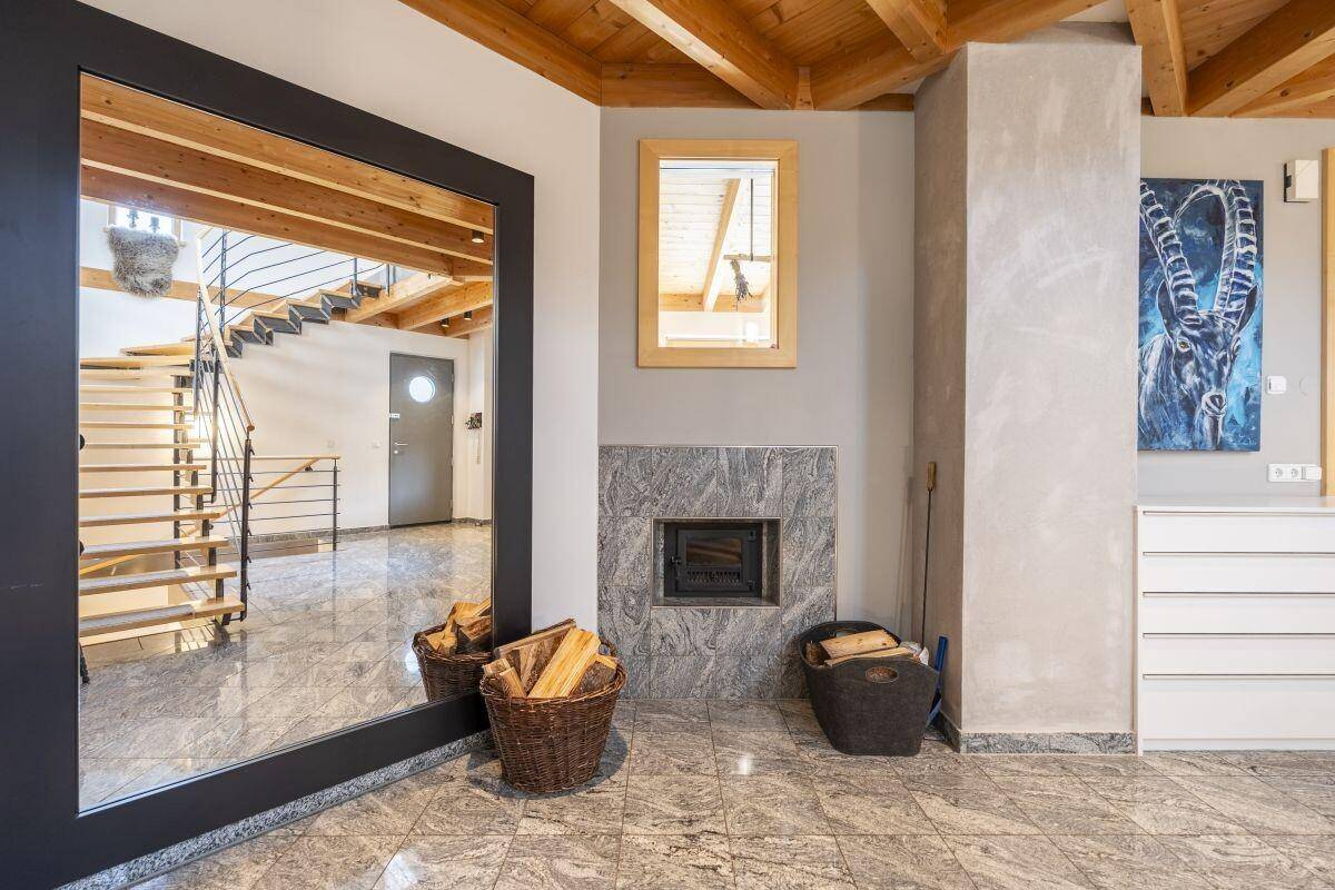 Heller Eingangsbereich mit Granitboden, Kamin und einer eleganten Holztreppe.