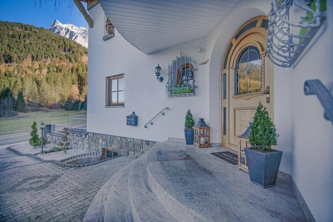 Detailansicht des Hauseingangs mit Holztür, Steinmauern und Blick auf die Berge.