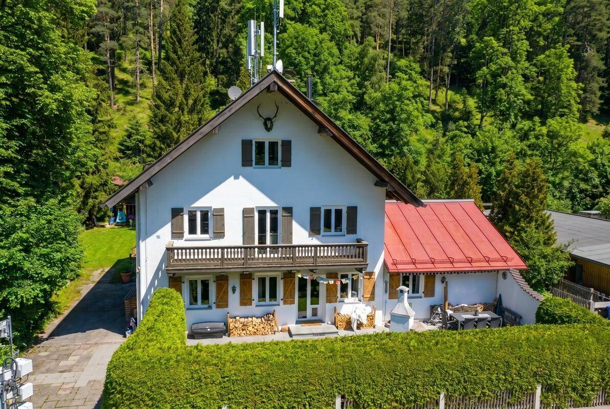 Traditionelles Einfamilienhaus im alpinen Stil mit Garten und umgeben von grünen Wäldern.
