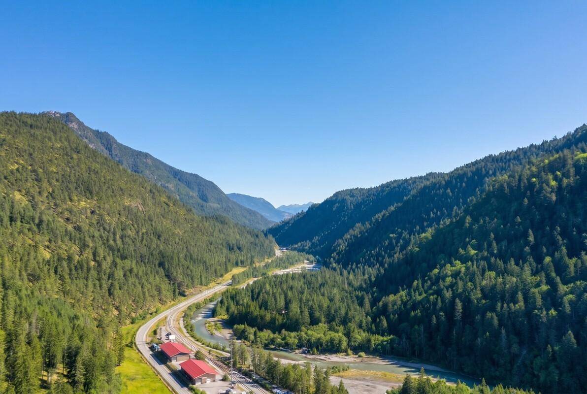 Weitläufiges Tal mit gewundener Straße, Fluss und dichten Wäldern unter klarem Himmel.
