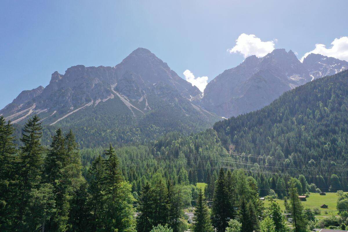 Beeindruckender Blick auf die schroffen Berggipfel und dichte Wälder unter strahlend blauem Himmel.