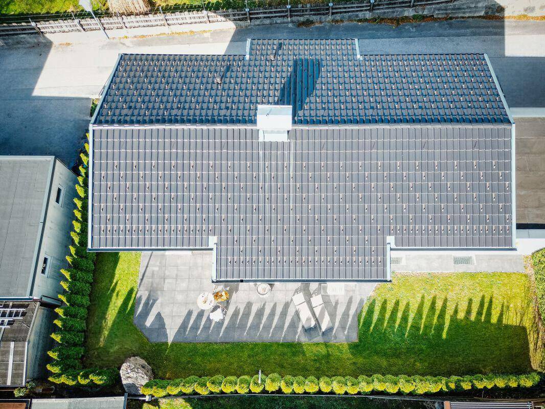 Luftaufnahme des Hauses mit Photovoltaikanlage auf dem Dach und gepflegtem Gartenbereich.